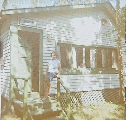A person standing on a porch of a house
Description automatically generated